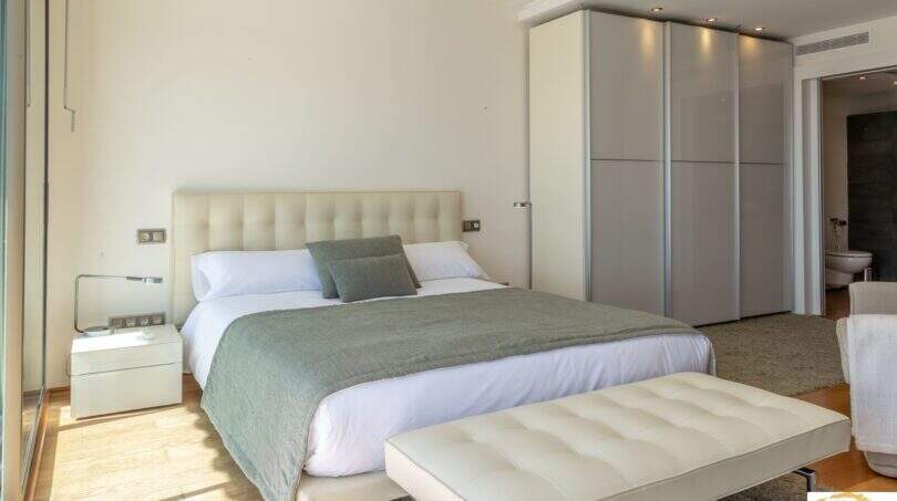 Dormitorio luminoso de la villa de lujo con cama doble, armario empotrado y baño en suite en Cala Magrana.