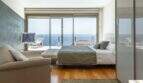 Dormitorio luminoso de la villa de lujo en Cala Magrana con cama doble, suelo de madera y terraza con vistas al mar.