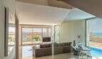Sala de estar moderna de la villa de lujo en Cala Magrana con barandilla de cristal, piscina y vistas al mar