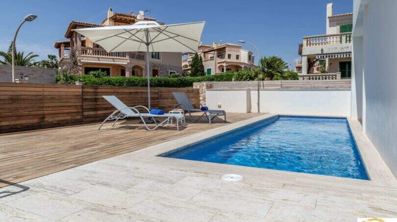 Piscina privada con terraza de madera, tumbonas y sombrilla de la villa de lujo en Cala Magrana, Porto Cristo