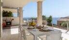 Terraza cubierta de la villa de lujo con mesa de comedor, vistas al mar y zona de barbacoa en Cala Magrana