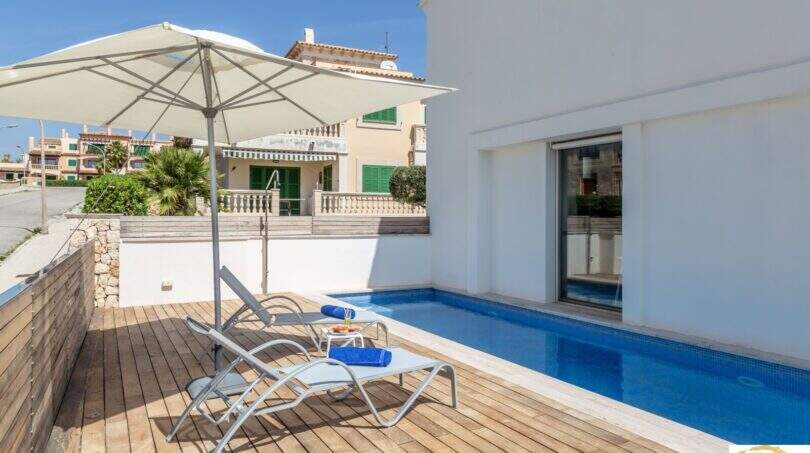 Terraza soleada con piscina, tumbonas y sombrilla de la villa de lujo en Cala Magrana, Porto Cristo