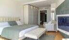 Dormitorio luminoso de la villa de lujo con cama doble, armario empotrado, televisor Samsung y baño en suite en Cala Magrana.