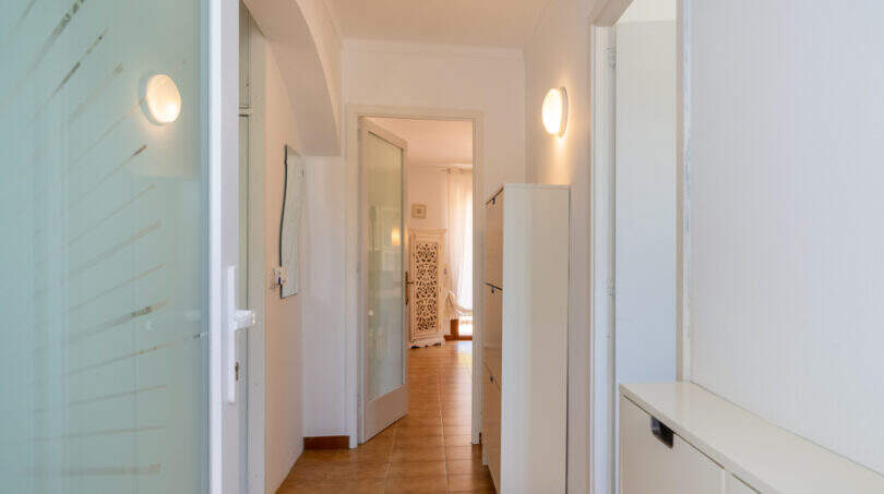 Heller Flur mit Terrakottaboden, Rundbogen und weißen Einbauschränken im Apartment Cala Murada