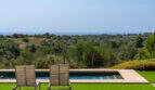 Infinity-Pool mit Holzliegen, Meerblick und üppiger Natur der Finca in Cales de Mallorca