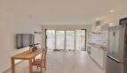 Luminoso salón-comedor con cocina abierta, acceso a terraza y suelo de baldosas moderno en apartamento de huéspedes, Marratxí