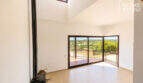 Helles Wohnzimmer mit Kaminofen, hoher Decke und großen Glasschiebetüren zur Terrasse mit Panoramablick, Ses Salines