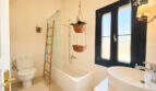 Helles Badezimmer mit Badewanne, Dusche, modernem Waschbecken und dekorativer Bambusleiter in Ses Salines