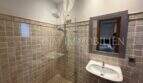 Badezimmer der Gästewohnung in Villa Marratxí mit Glasdusche, Natursteinwänden und elegantem Wandspiegel