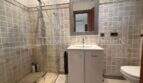 Baño moderno con ducha de cristal, mueble lavabo blanco y baldosas de piedra natural en las paredes en villa Marratxí