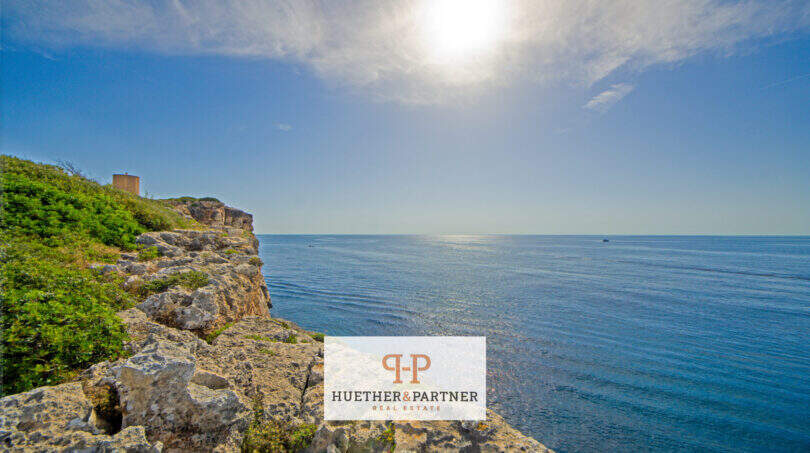 Felsküste in 1. Meereslinie Porto Cristo mit blauem Mittelmeer, historischem Wachturm und Panoramablick