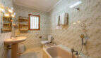 Cuarto de baño de la villa con azulejos de mármol, bañera, bidé, inodoro y toallero en Cala Murada
