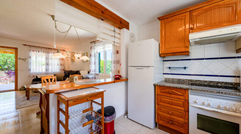 Helle Küche mit Holzfronten, Granitarbeitsplatte, Kochinsel und Durchblick ins Wohnzimmer in Cala Murada