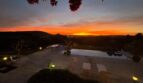 Luxusfinca Son Carrió: beleuchteter Pool mit Bougainvillea und dramatischem Sonnenuntergang über der Landschaft