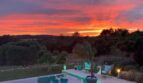 Luxusfinca Son Carrió: beleuchteter Pool bei dramatischem Sonnenuntergang mit Gartenanlage und Panoramablick