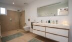Modernes Badezimmer der Luxusfinca in Son Carrió mit Doppelwaschbecken, begehbarer Regendusche und hochwertigen Materialien.