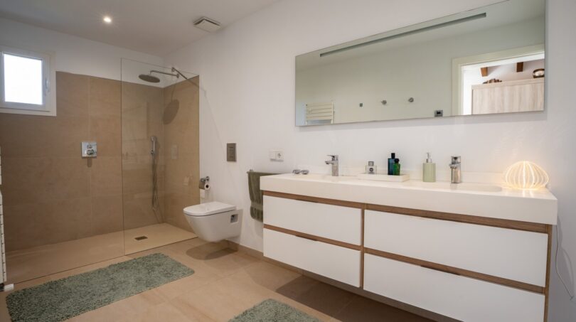 Modernes Badezimmer der Luxusfinca in Son Carrió mit Doppelwaschbecken, begehbarer Regendusche und hochwertigen Materialien.