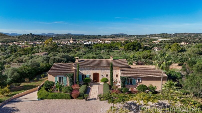 Luftaufnahme einer mediterranen Luxusfinca in Son Carrió mit Terrakottadach, Natursteinmauern und grüner Hügellandschaft.
