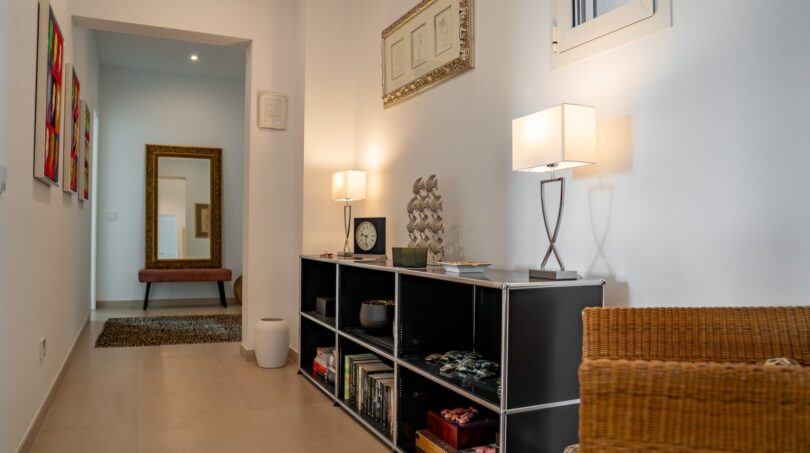 Eleganter Flurbereich der Luxusfinca in Son Carrió mit schwarzem Sideboard, Dekorleuchten und goldenem Wandspiegel.