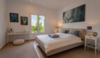 Helles Schlafzimmer der Luxusfinca in Son Carrió mit Doppelbett, Kunstwerken und Gartenblick