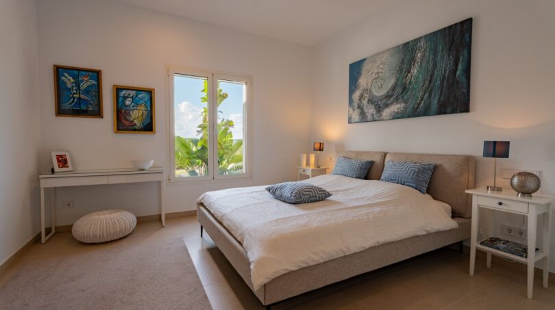 Helles Schlafzimmer der Luxusfinca in Son Carrió mit Doppelbett, Kunstwerken und Gartenblick