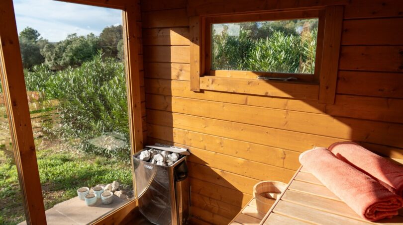 Holzsauna mit Saunaofen, Ruheliege und Panoramablick auf die grüne Landschaft der Luxusfinca in Son Carrió