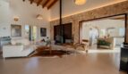 Lichtdurchflutetes Wohnzimmer der Luxusfinca in Son Carrió mit Natursteinwand, Kamin und offenem Küchenbereich