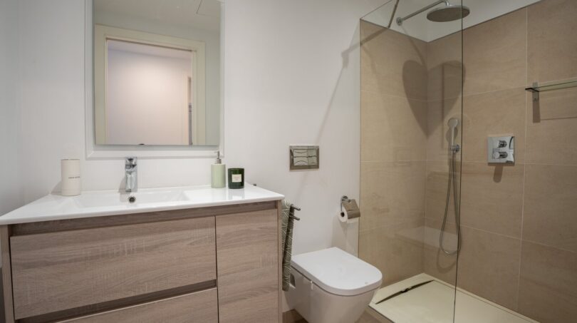 Modernes Badezimmer der Luxusfinca in Son Carrió mit Walk-in-Dusche, Holzwaschtisch und WC.