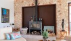 Wohnzimmer der Luxusfinca in Son Carrió mit modernem Kaminofen und rustikaler Natursteinwand