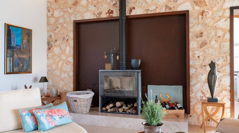Wohnzimmer der Luxusfinca in Son Carrió mit modernem Kaminofen und rustikaler Natursteinwand