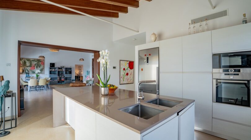 Moderne Einbauküche mit Kochinsel, Bosch-Geräten und Blick ins Wohnzimmer der Luxusfinca in Son Carrió