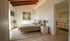 Helles Schlafzimmer der Luxusfinca in Son Carrió mit Holzbalkendecke, Doppelbett und angrenzendem Badezimmer