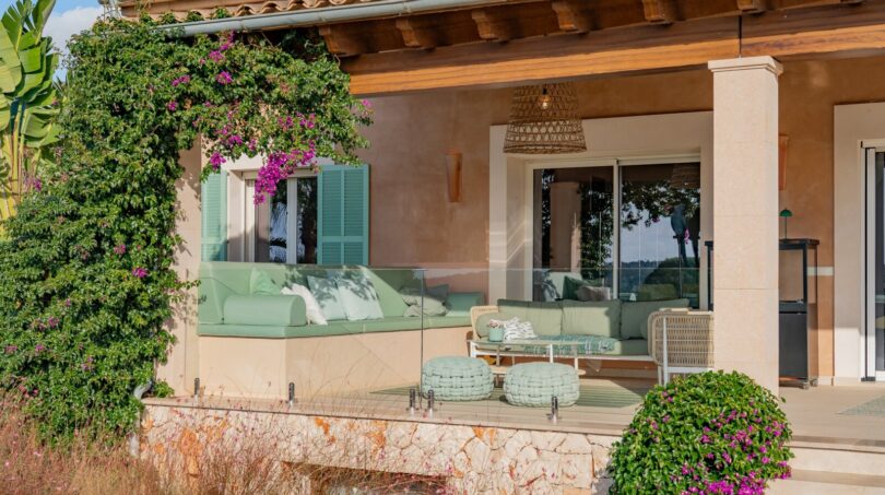 Luxusfinca Son Carrió: Elegante Terrasse mit mintgrüner Lounge, Holzveranda und mediterranem Garten mit Bougainvillea