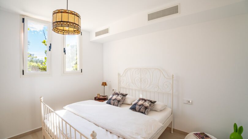 Helles Schlafzimmer der Luxusfinca in Son Carrió mit weißem Metallbett, Tiffany-Lampe und Klimaanlage.