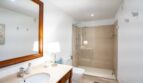 Elegantes Badezimmer der Luxusfinca in Son Carrió mit Glasdusche, Holzwaschtisch und hochwertigen Materialien.