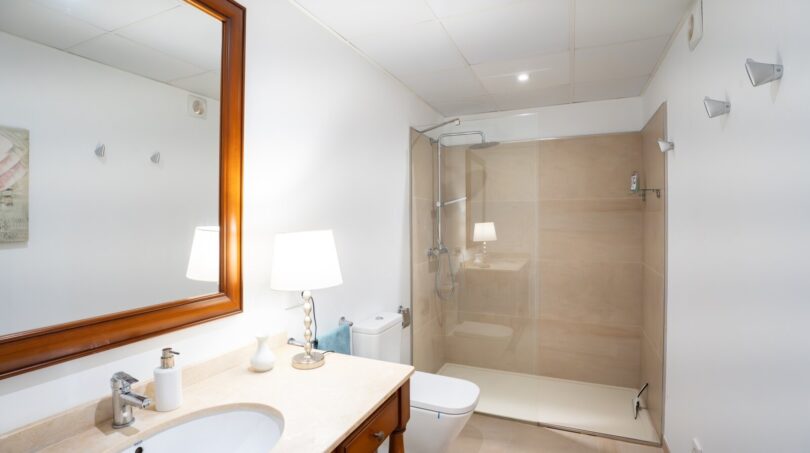 Elegantes Badezimmer der Luxusfinca in Son Carrió mit Glasdusche, Holzwaschtisch und hochwertigen Materialien.