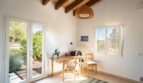 Helles Arbeitszimmer der Luxusfinca in Son Carrió mit Holzbalkendecke, Terrassenzugang und Gartenblick.
