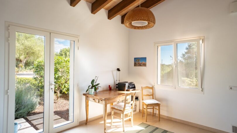 Helles Arbeitszimmer der Luxusfinca in Son Carrió mit Holzbalkendecke, Terrassenzugang und Gartenblick.