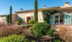 Außenansicht Luxusfinca Son Carrió mit Natursteinmauern, grünen Fensterläden und mediterranem Garten