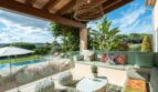 Überdachte Terrasse mit mint-grüner Lounge, Pool und Gartenblick der Luxusfinca in Son Carrió