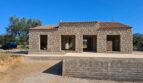 Rohbau einer Naturstein-Finca in Artà mit Terrakotta-Ziegeldach und mediterraner Architektur unter blauem Himmel.