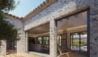 Holzterrasse einer Neubau-Finca in Artà mit Natursteinwänden, Terrakotta-Dach und großen Glasfronten zum Innenbereich
