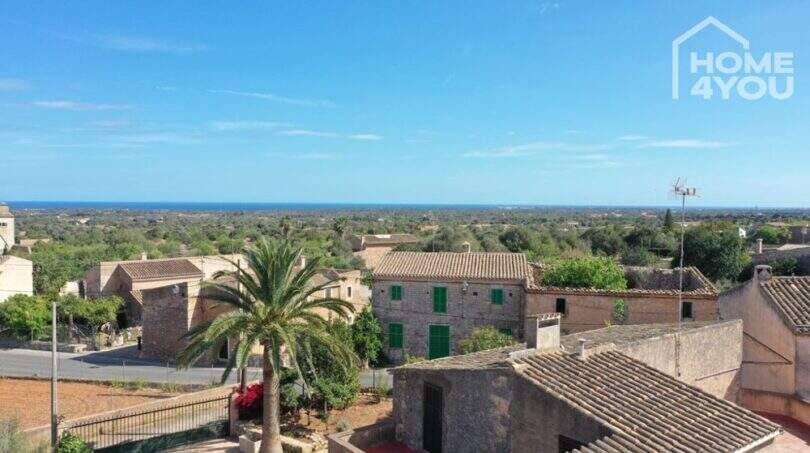 Panoramablick über S'Alqueria Blanca mit Meerblick, traditionellen Steinhäusern und mediterraner Vegetation.