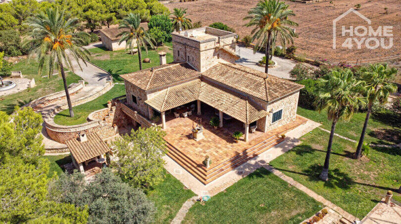 Luftaufnahme einer exklusiven Finca in Colònia de Sant Jordi mit Natursteinvilla, Terrasse, Palmen und weitläufigem Grundstück.