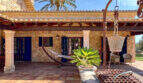 Rustikale Finca-Terrasse mit Natursteinmauer, Hängematte, Pergola und Palmen in Colònia de Sant Jordi