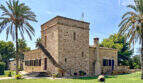 Außenansicht exklusive Finca in Colònia de Sant Jordi: historischer Sandsteinturm mit Palmen und gepflegtem Rasen