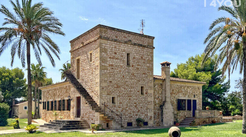 Außenansicht exklusive Finca in Colònia de Sant Jordi: historischer Sandsteinturm mit Palmen und gepflegtem Rasen