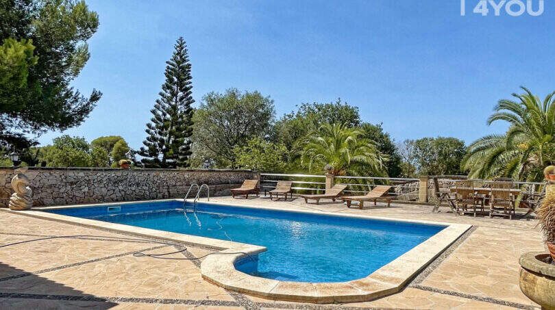 Großer Pool mit Natursteinteasse, Liegestühlen und üppigem Grün der exklusiven Finca in Colònia de Sant Jordi