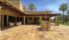 Weitläufige Naturstein-Terrasse mit Brunnen, Pergola und Loungebereich der exklusiven Finca in Colònia de Sant Jordi