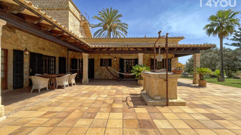 Weitläufige Naturstein-Terrasse mit Brunnen, Pergola und Loungebereich der exklusiven Finca in Colònia de Sant Jordi